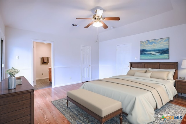 bedroom featuring light wood-type flooring, visible vents, ensuite bath, and baseboards