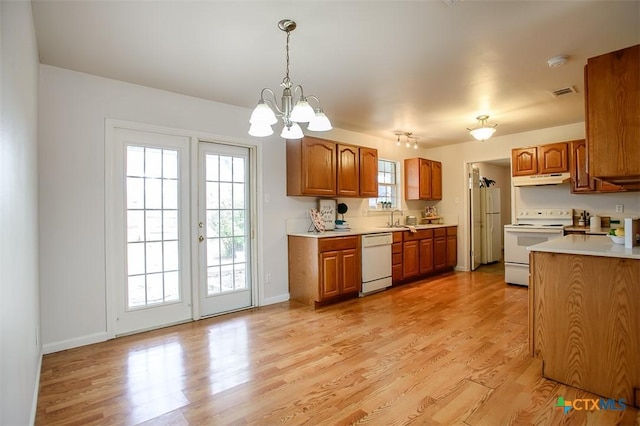 kitchen with light wood-style flooring, white appliances, a sink, light countertops, and brown cabinetry