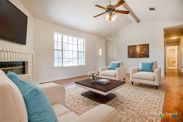 living room featuring vaulted ceiling with beams, baseboards, visible vents, and wood finished floors