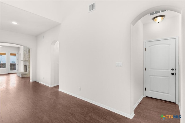 entryway with arched walkways, dark wood finished floors, baseboards, and visible vents