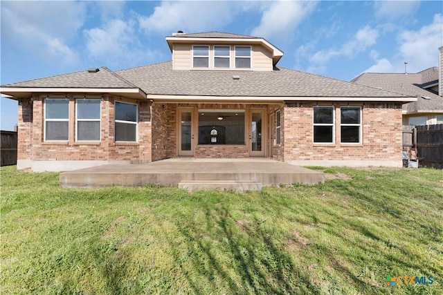 rear view of house with a lawn, brick siding, and a patio