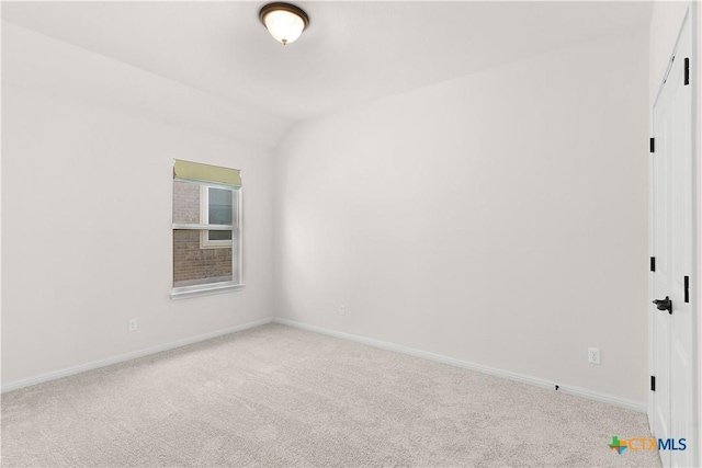 empty room featuring vaulted ceiling, baseboards, and light carpet