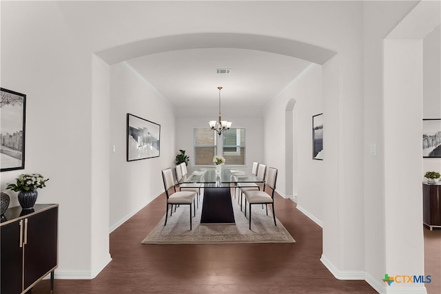 dining area featuring crown molding, a chandelier, arched walkways, visible vents, and dark wood-style floors