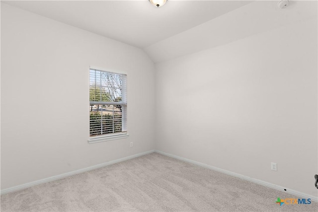 empty room featuring carpet floors, lofted ceiling, and baseboards
