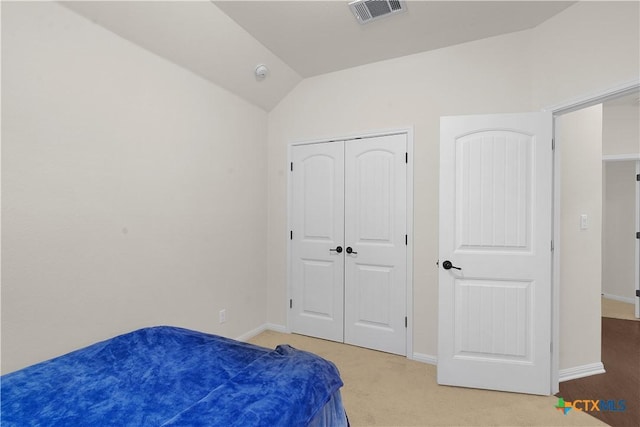 carpeted bedroom with vaulted ceiling and a closet