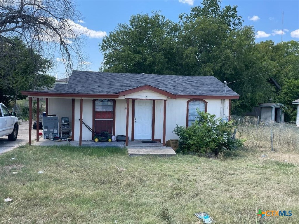 ranch-style home featuring a front lawn and a shed