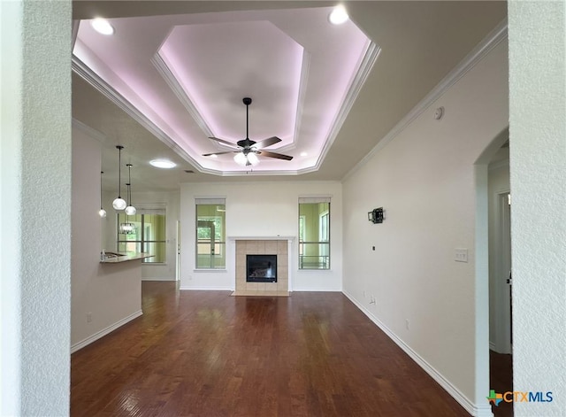 1403 Excel Dr, Killeen, TX 76542 - unfurnished living room with ceiling fan, a raised ceiling, wood finished floors, a tiled fireplace, and crown molding