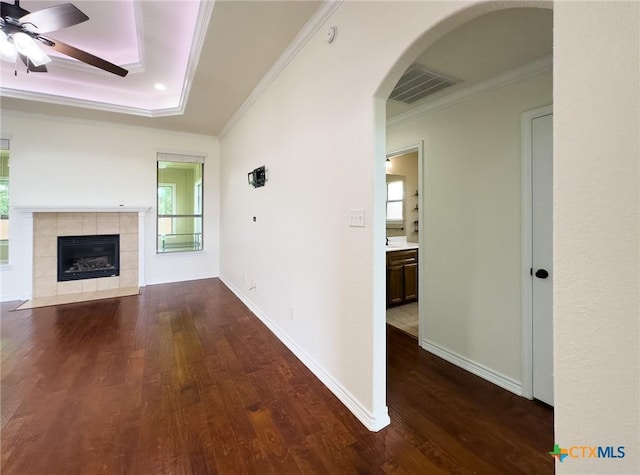 1403 Excel Dr, Killeen, TX 76542 - unfurnished living room with ornamental molding, a ceiling fan, dark wood-style flooring, arched walkways, and a tiled fireplace