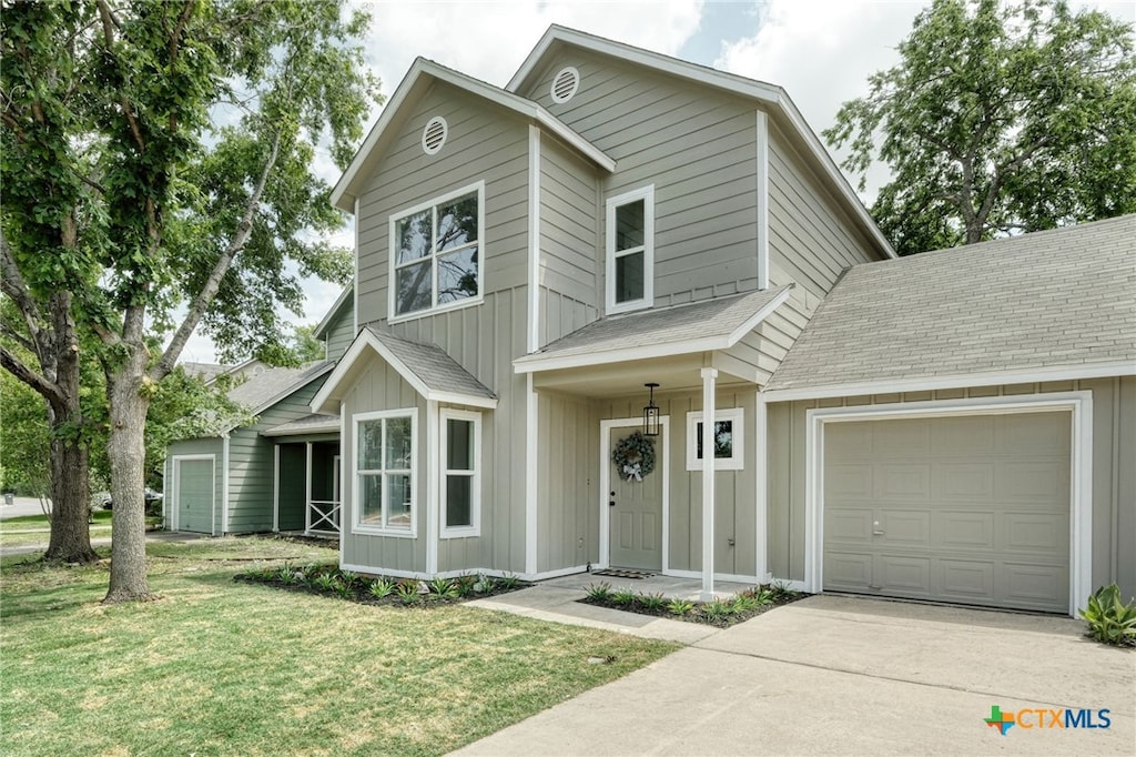 1008 E 3rd St, Georgetown, TX 78626 - view of front of house with a shingled roof, a garage, driveway, board and batten siding, and a front yard