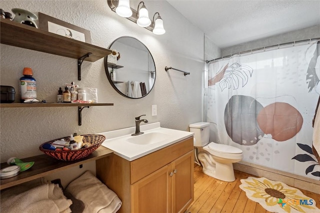 bathroom featuring a shower with curtain, vanity, a textured ceiling, hardwood / wood-style flooring, and toilet