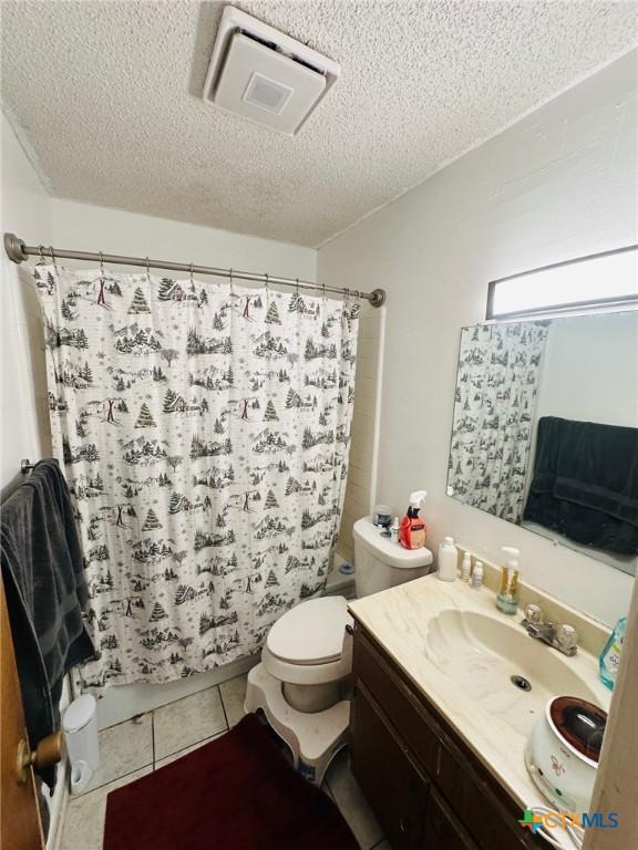218 Monterrey Dr, Victoria, TX 77904 - full bath with toilet, a textured ceiling, vanity, a shower with shower curtain, and tile patterned flooring