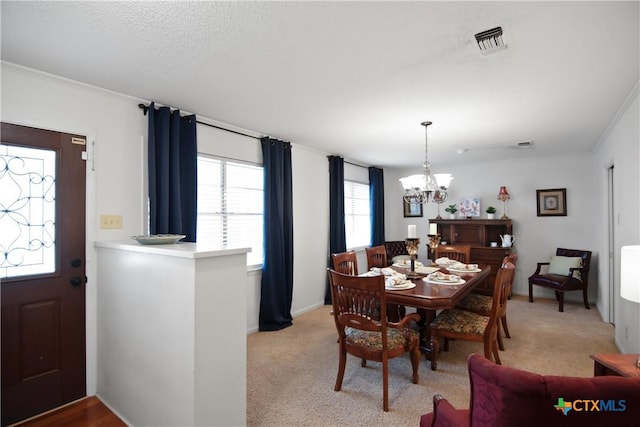 carpeted dining room featuring ornamental molding and an inviting chandelier