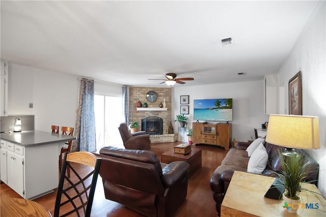 living room featuring ceiling fan, a brick fireplace, and dark hardwood / wood-style floors