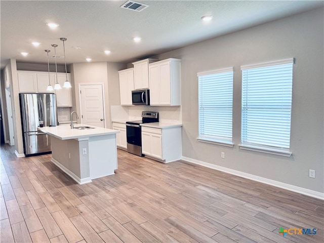 kitchen featuring sink, white cabinetry, hanging light fixtures, a center island with sink, and appliances with stainless steel finishes