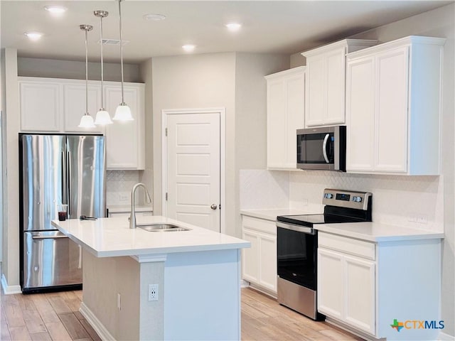 kitchen with sink, white cabinets, hanging light fixtures, a kitchen island with sink, and appliances with stainless steel finishes