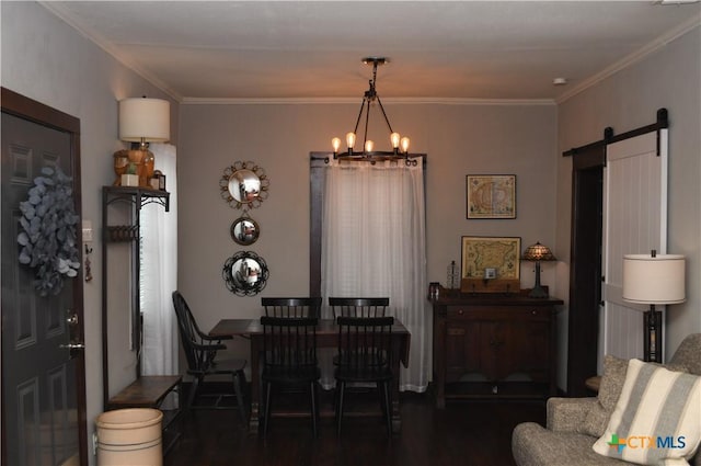 dining room with wood finished floors, a chandelier, a barn door, ornamental molding, and baseboards
