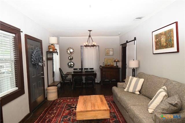 living area with a barn door, dark wood finished floors, a chandelier, and ornamental molding