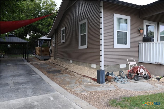 view of side of property featuring a gazebo, crawl space, and concrete driveway