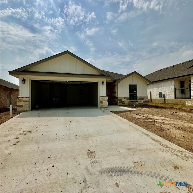 5113 Rose Petal Ct, Killeen, TX 76542 - view of front of property featuring board and batten siding, driveway, a garage, stone siding, and a shingled roof
