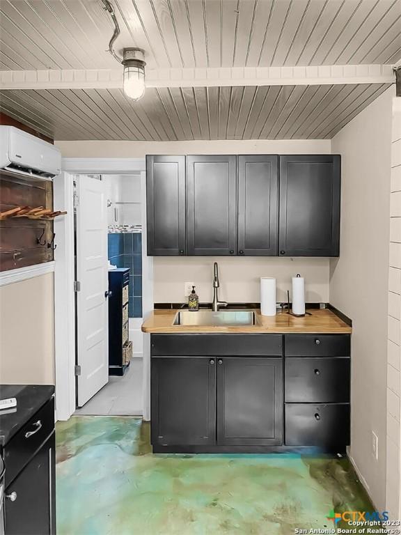 kitchen with butcher block countertops, an AC wall unit, and sink