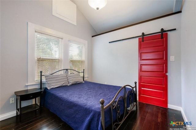 bedroom with dark hardwood / wood-style floors, a barn door, and lofted ceiling