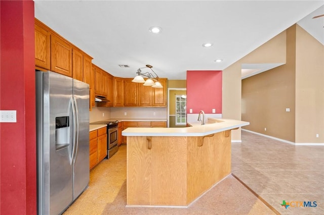 kitchen featuring sink, a breakfast bar, hanging light fixtures, stainless steel appliances, and an island with sink