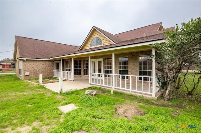 rear view of house featuring a yard and covered porch