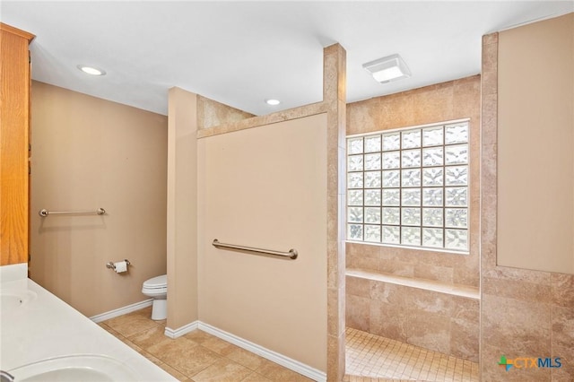 bathroom with tiled shower, tile patterned floors, toilet, and vanity