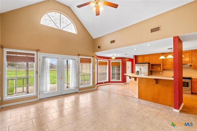 kitchen with french doors, appliances with stainless steel finishes, a breakfast bar, and light tile patterned floors