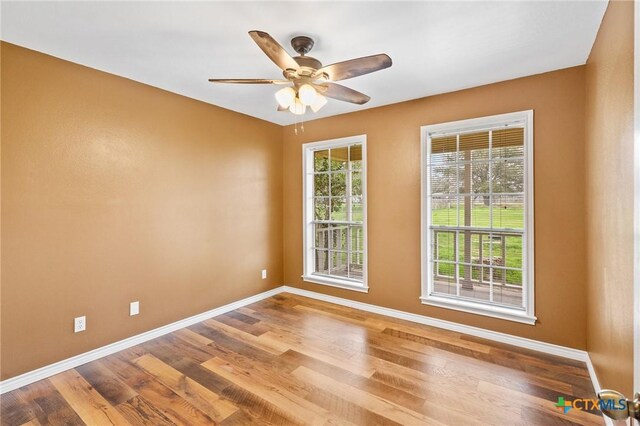 empty room with hardwood / wood-style floors and ceiling fan