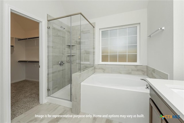 full bathroom with vanity, a shower stall, a spacious closet, and a bath