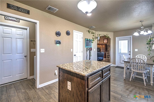 kitchen featuring a notable chandelier, dark hardwood / wood-style floors, a kitchen island, and hanging light fixtures