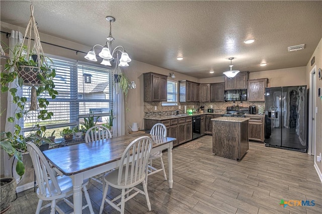 dining area featuring light hardwood / wood-style floors, a healthy amount of sunlight, a textured ceiling, and an inviting chandelier