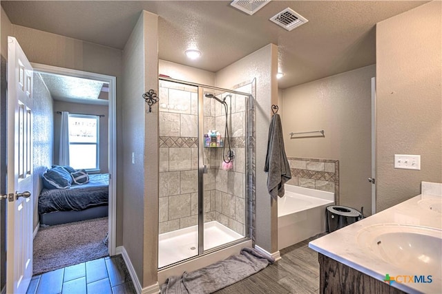 bathroom with vanity, shower with separate bathtub, and a textured ceiling