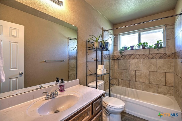 full bathroom featuring vanity, a textured ceiling, tiled shower / bath combo, hardwood / wood-style flooring, and toilet