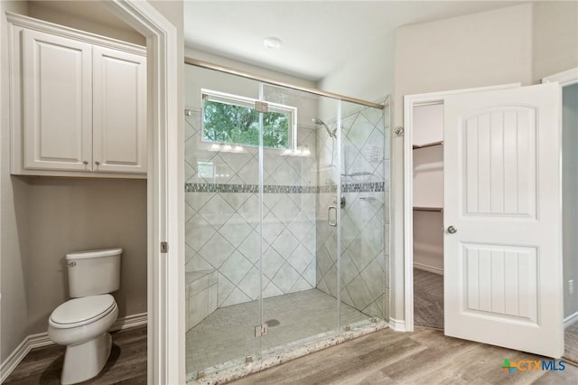 4049 Hickory Forrest Dr, Seguin, TX 78155 - bathroom featuring wood finished floors, a shower stall, toilet, a spacious closet, and baseboards