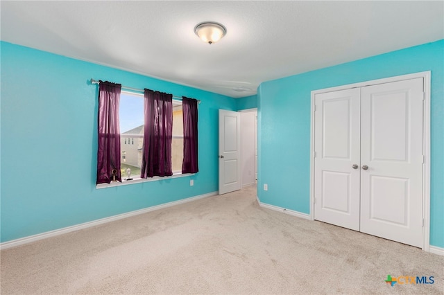 unfurnished bedroom with a closet and light colored carpet