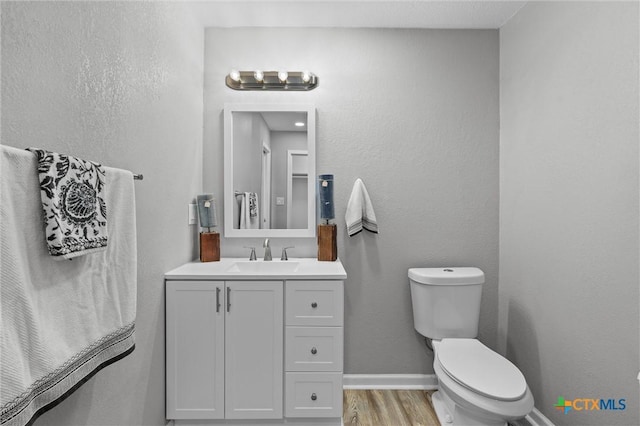 bathroom with hardwood / wood-style floors, vanity, and toilet