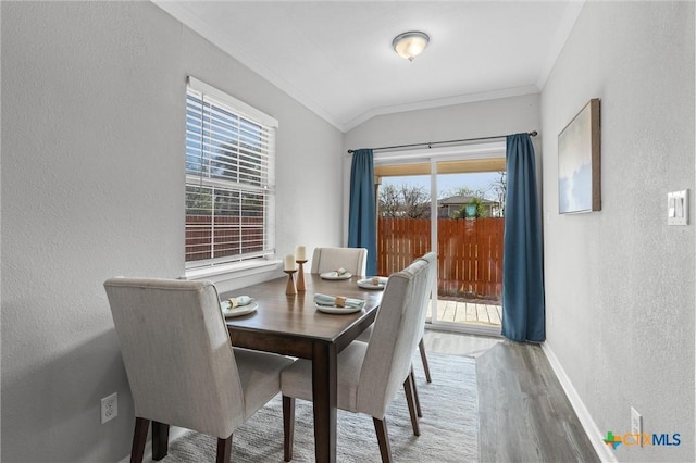 dining room featuring hardwood / wood-style flooring, plenty of natural light, lofted ceiling, and crown molding