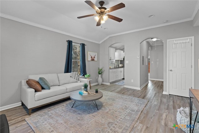 living room with ceiling fan, light hardwood / wood-style flooring, crown molding, and vaulted ceiling