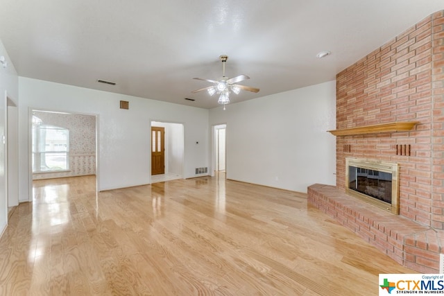 unfurnished living room featuring a brick fireplace, ceiling fan, and light hardwood / wood-style flooring