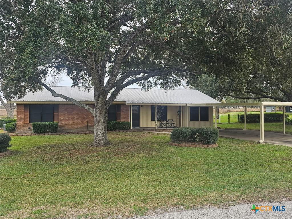 ranch-style house featuring a carport and a front lawn