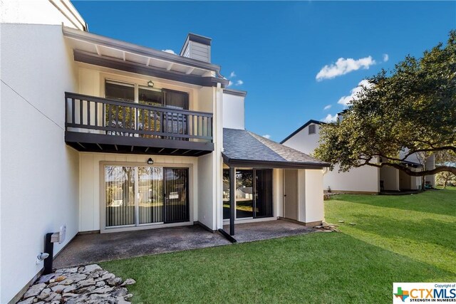 rear view of house featuring a yard, a balcony, and a patio