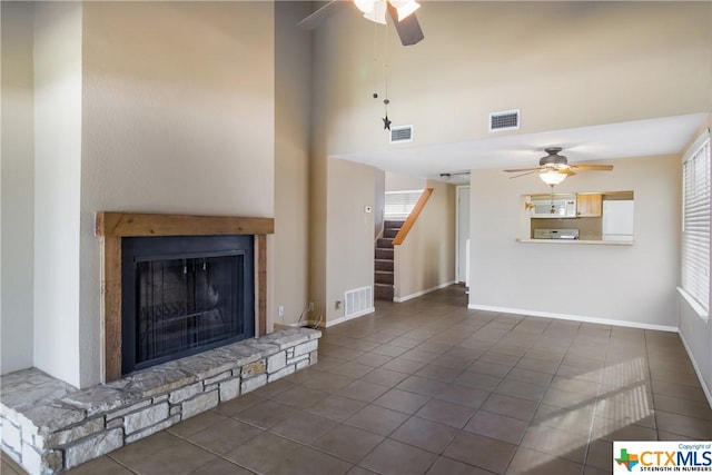 unfurnished living room with ceiling fan, dark tile patterned flooring, and a fireplace