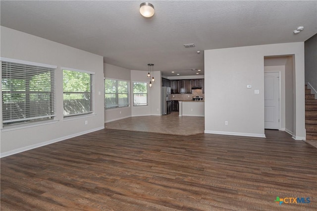 253 Flushing, New Braunfels, TX 78130 - unfurnished living room featuring dark wood-type flooring, baseboards, visible vents, and stairs