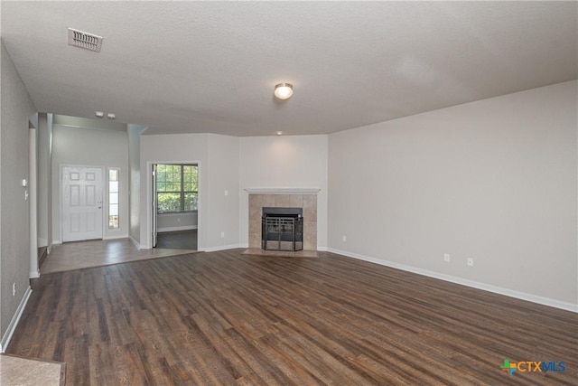 253 Flushing, New Braunfels, TX 78130 - unfurnished living room with dark wood-type flooring, visible vents, baseboards, and a tile fireplace