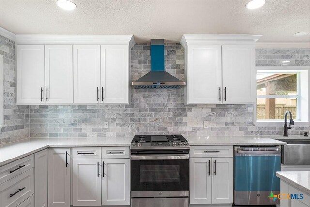 111 Warwick Glen St, Victoria, TX 77904 - kitchen featuring stainless steel appliances, wall chimney exhaust hood, a textured ceiling, light countertops, and white cabinets