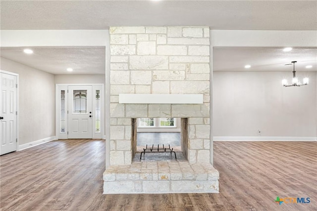 111 Warwick Glen St, Victoria, TX 77904 - unfurnished living room featuring wood finished floors, a textured ceiling, recessed lighting, a fireplace, and a chandelier