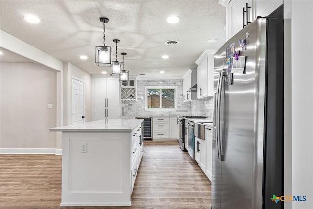 111 Warwick Glen St, Victoria, TX 77904 - kitchen with appliances with stainless steel finishes, beverage cooler, light wood finished floors, tasteful backsplash, and white cabinets