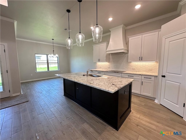 2032 Yarrow Rd, Temple, TX 76502 - kitchen with premium range hood, white cabinetry, a center island with sink, tasteful backsplash, and light wood finished floors